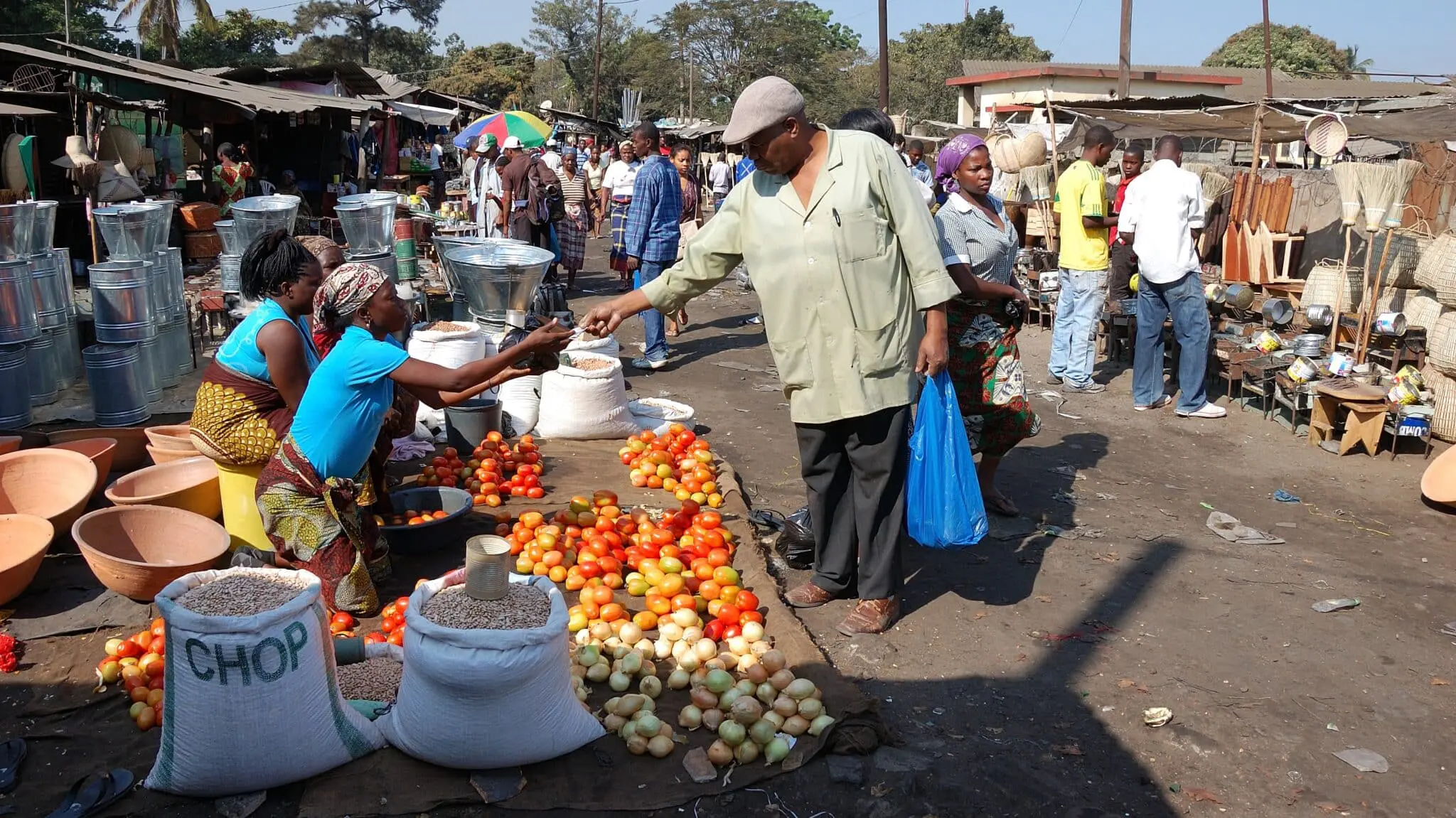 un homme achète des fruits et légumes dans les rues du marché à Maputo