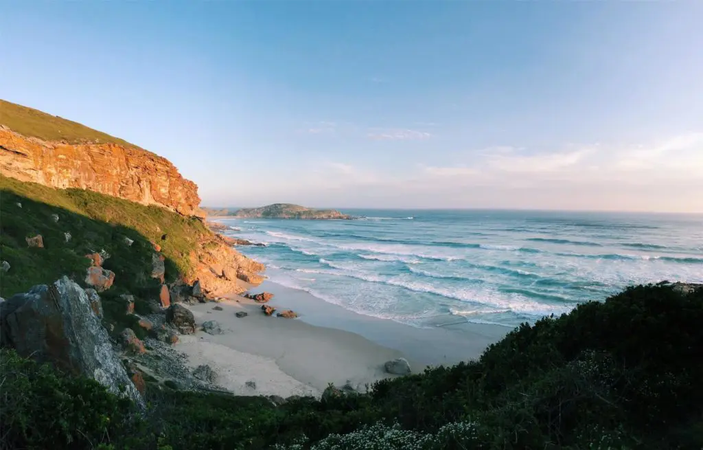 Paysage donnant sur la plage de Robberg ainsi que sur les rochers orangés de la promenade