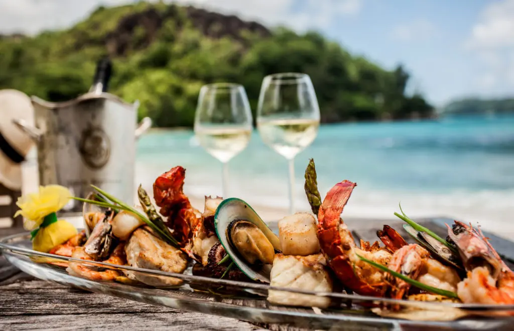 Beau plateau de fruits de mer et vin blanc sur une plage paradisiaque