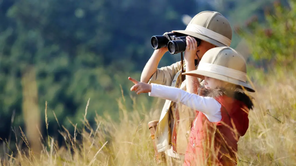 Deux enfants en safari avec des jumelles observent l'horizon