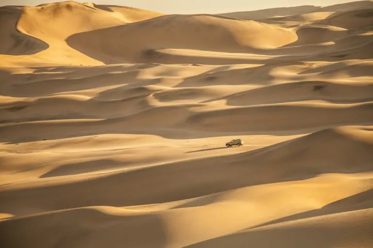 Un 4x4 évolue sur les vastes dunes ensoleillées du désert du Namib