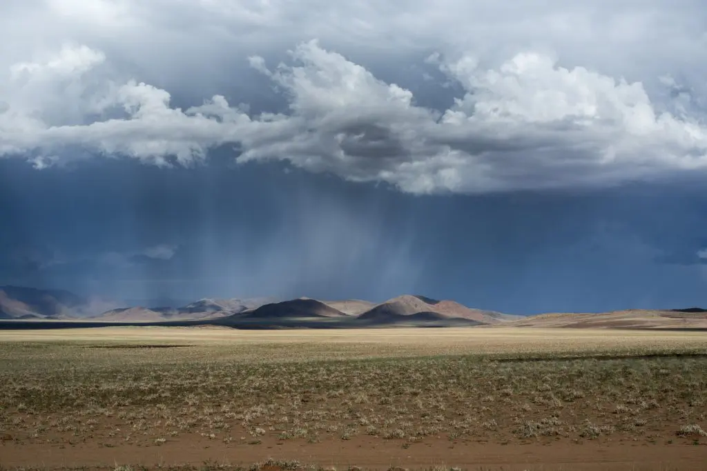 Ciel sombre chargé de nuages et de pluie sur un paysage aride