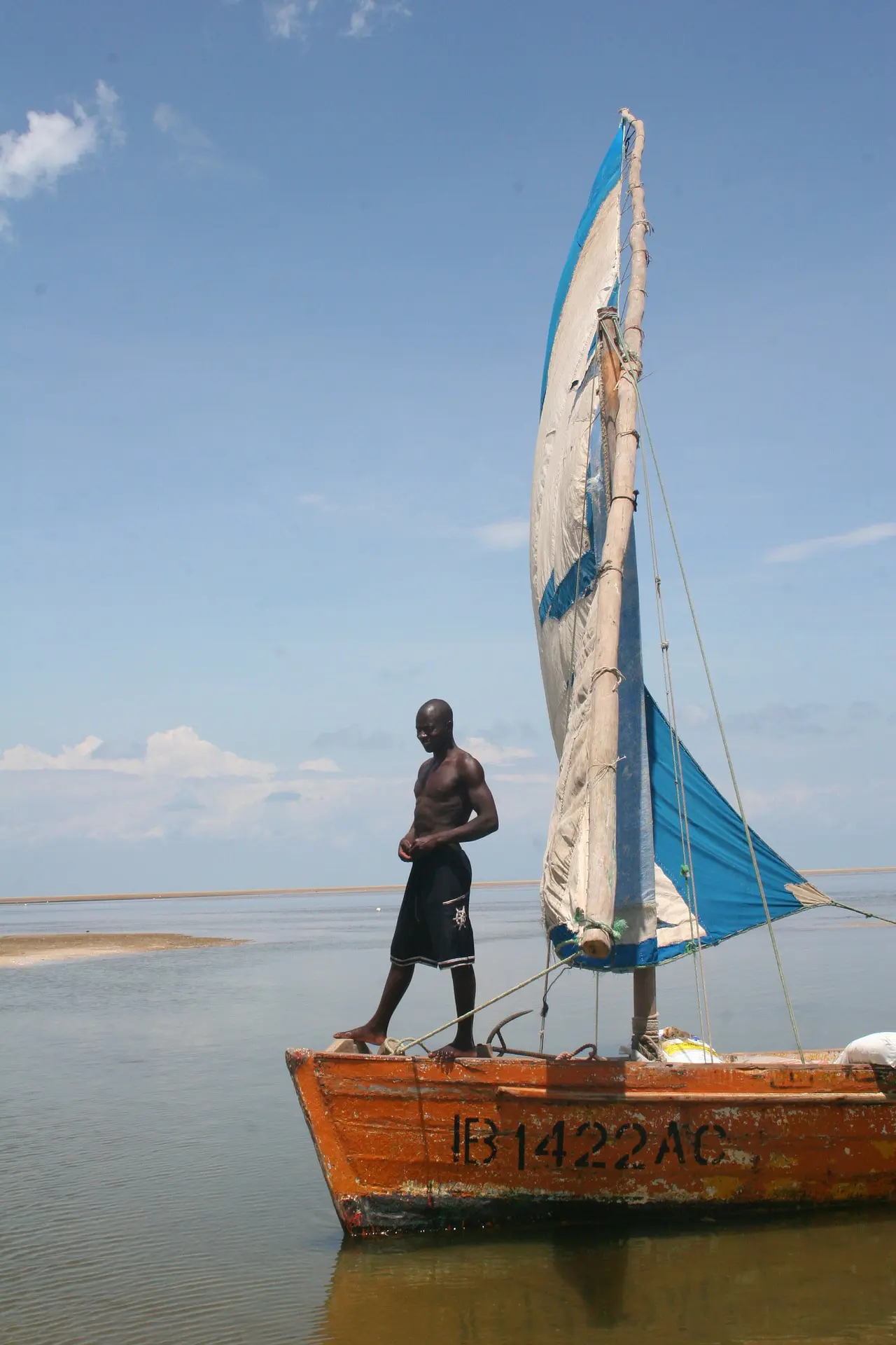Un homme debout sur un boutre, dans les eaux du Mozambique