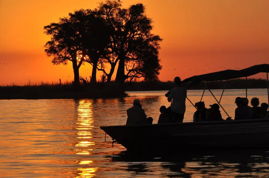 Des touristes en bateau admirent le coucher de soleil au ciel orange