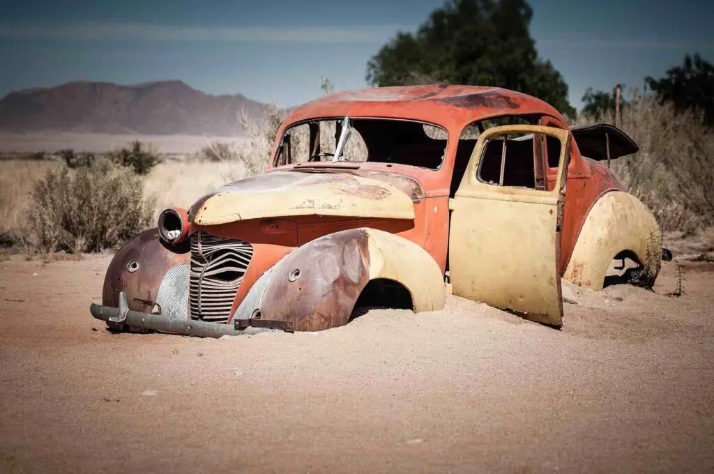 Une carcasse de voiture coccinelle est ensevelie sous le sable