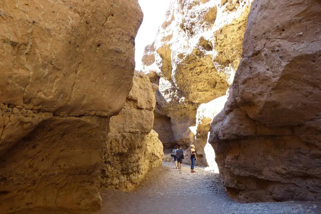 La tête levée, deux personnes marchent à l'intérieur d'un canyon