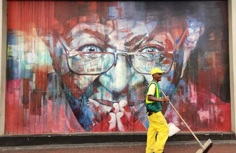 Un agent d'entretien passe devant le street art de Desmond Tutu