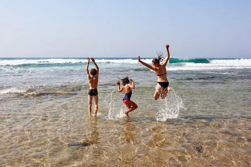 Un mère et ses 2 enfants s'amusent en vacances en sautant dans l'eau