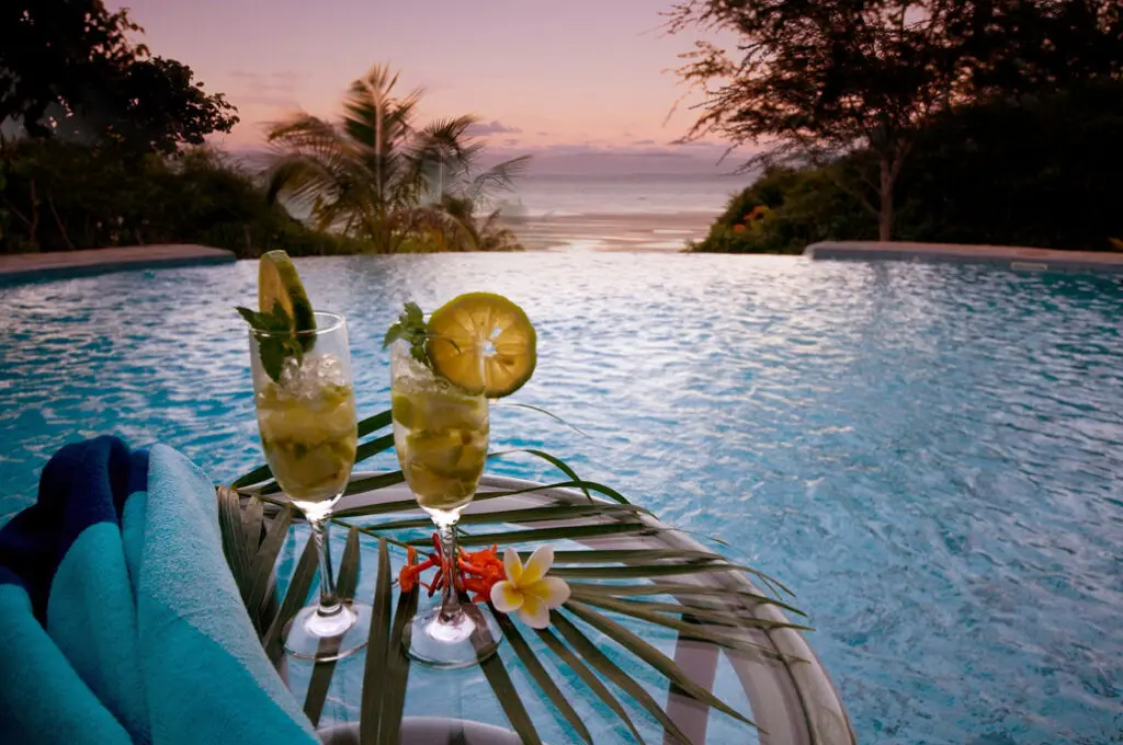 2 cocktails en bord de piscine donnant sur la mer au coucher du soleil
