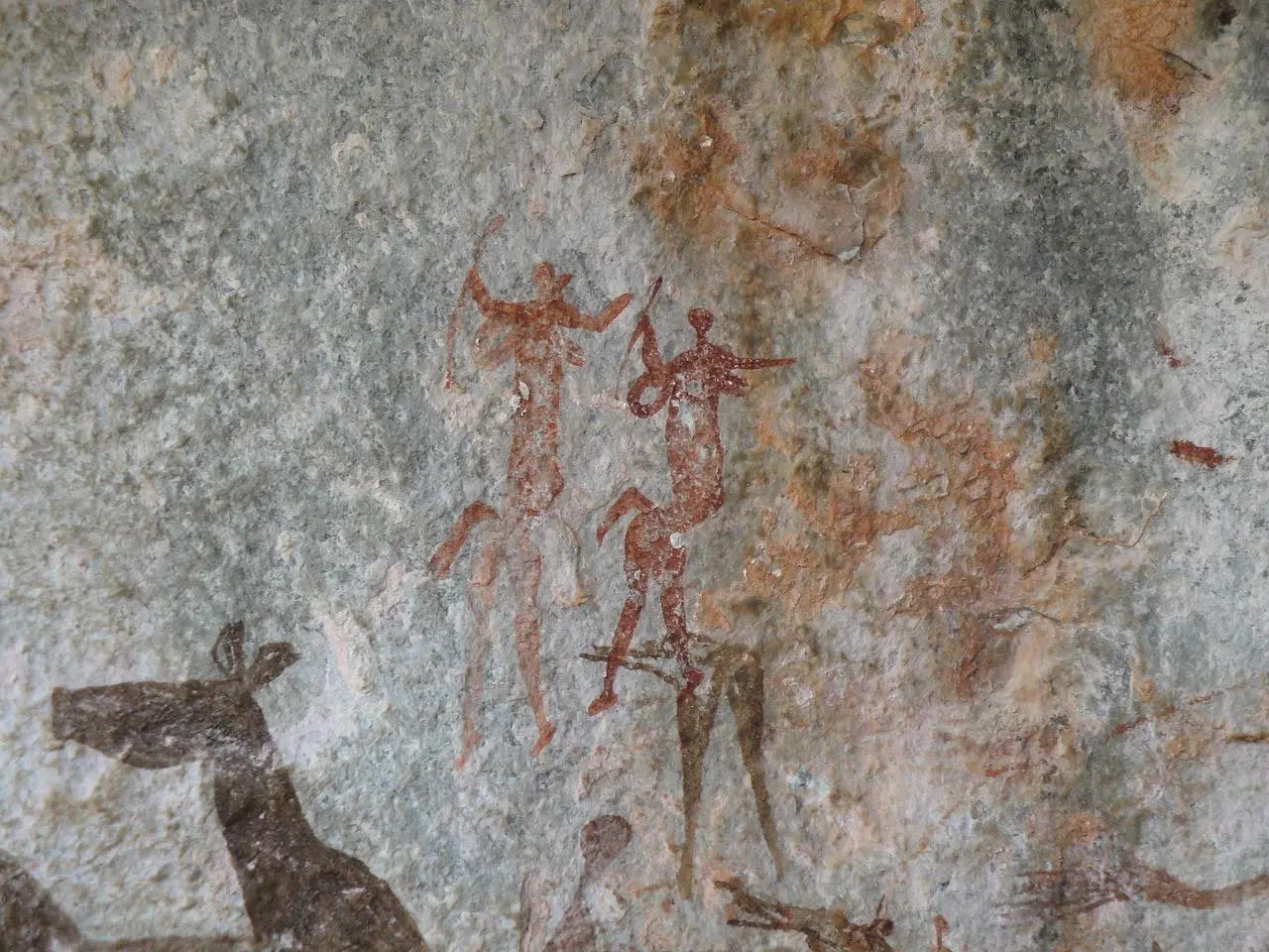 Des peintures rupestres de chasseurs et d'animaux sur un rocher