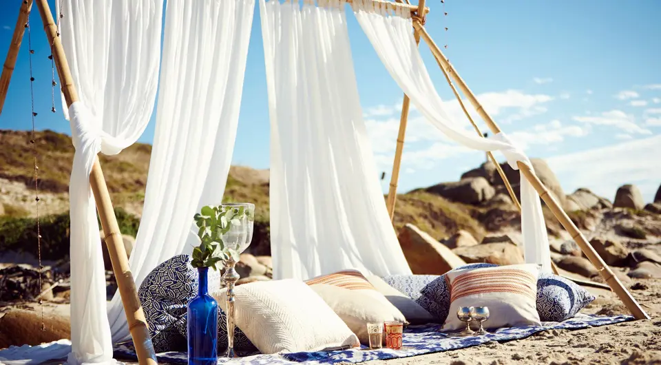 Un pique-nique à la plage avec coussins, voile et belles installations