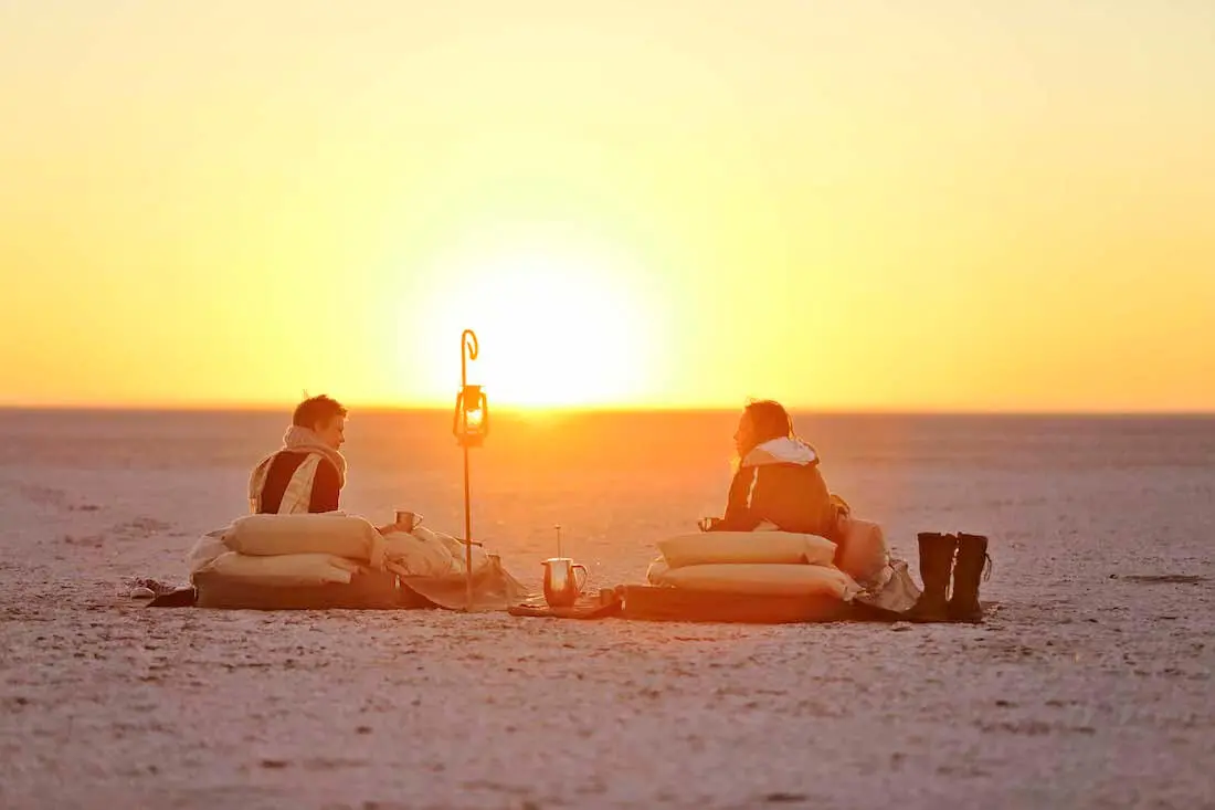 2 personnes face au lever du soleil dans les pan de makgadikgadi