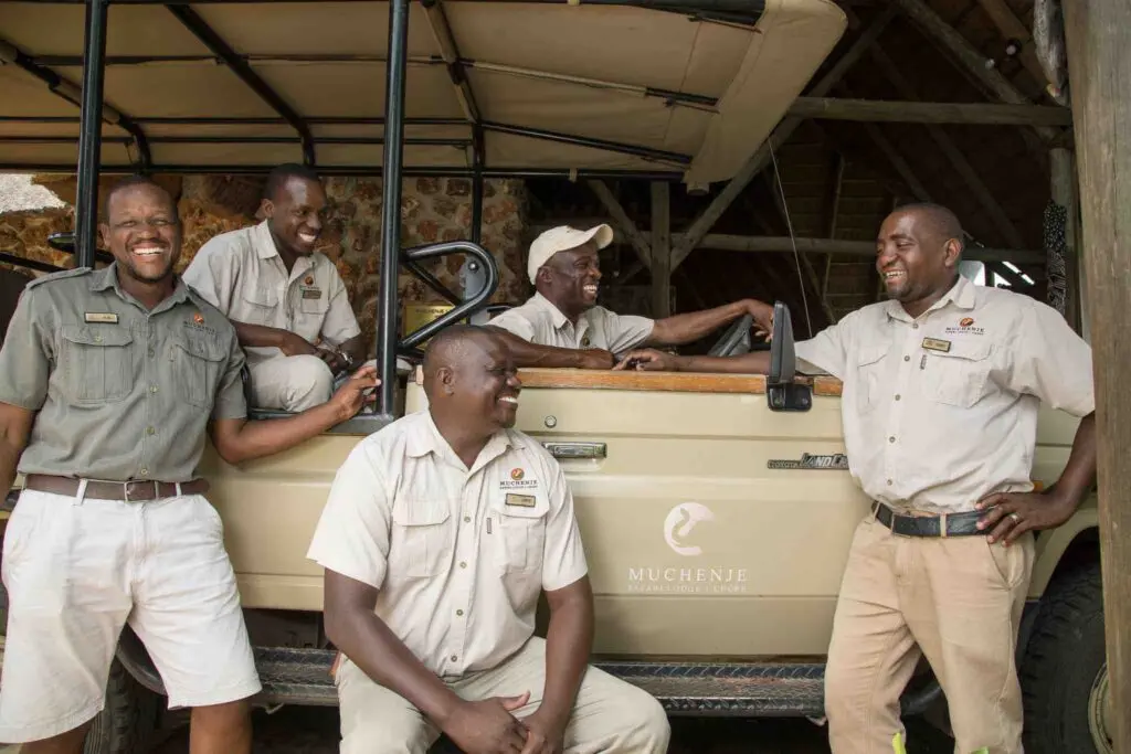 Personnel souriant de l'eco lodge posant sur un 4x4 