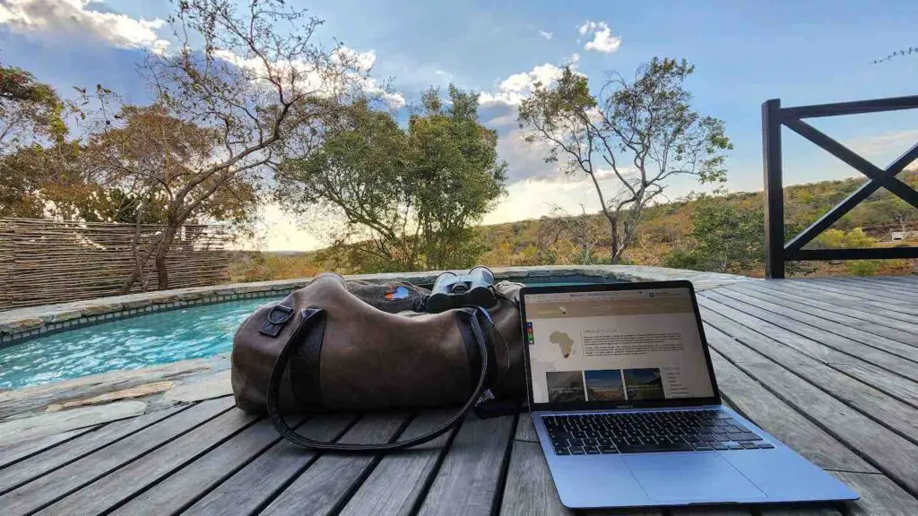 Un sac de voyage posé à côté d'un ordinateur en terrasse d'un lodge