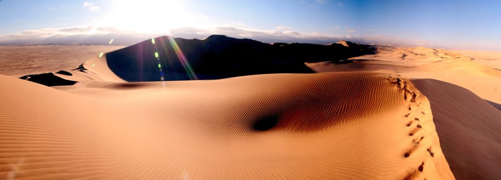 Sous un grand ciel bleu, le soleil brille au firmament sur les dunes