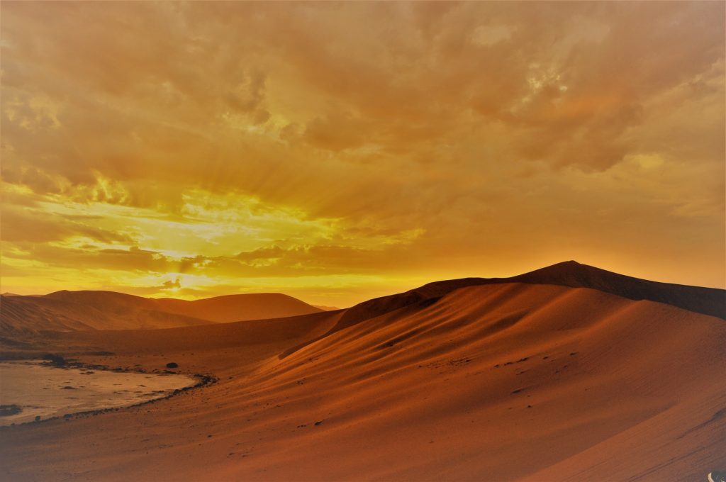 Chaleur dans les dunes avec un ciel nuageux orangé par le soleil
