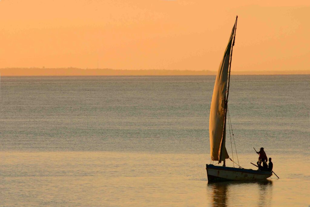 Au coucher du soleil, un boutre évolue sur l'océan indien
