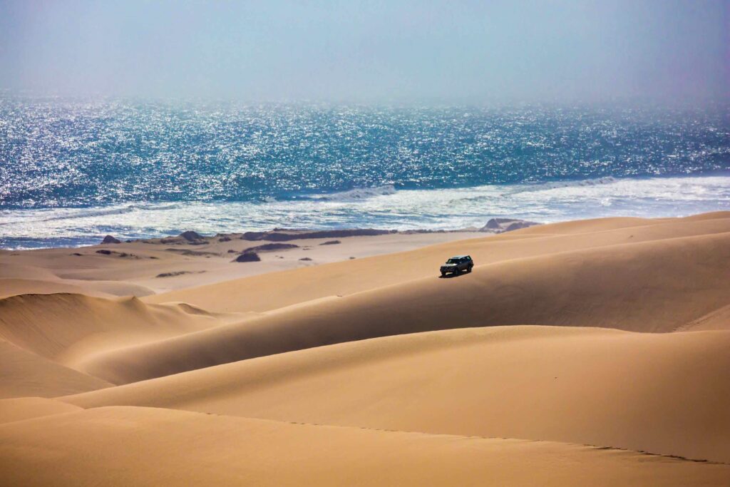 Un 4x4 roule sur les dunes de sandwich harbour longeant l'océan