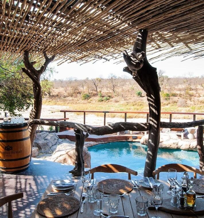 Vue sur le deck, la piscine et le bush depuis une table dressée