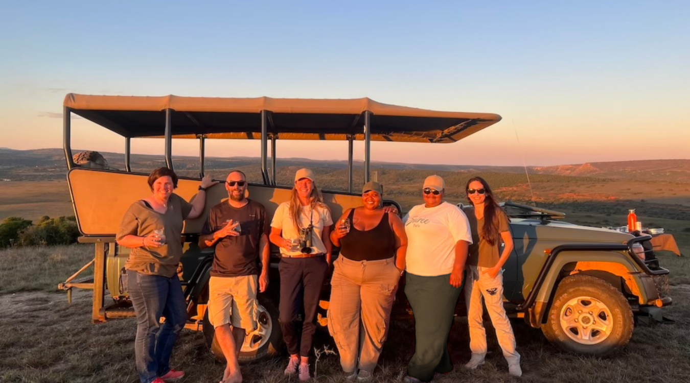 L'équipe d'Ekima devant un 4x4 en safari au coucher du soleil